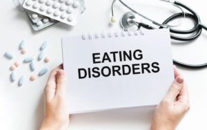 Text with words Eating Disorders on a Notebook with Doctor Tools and Medication