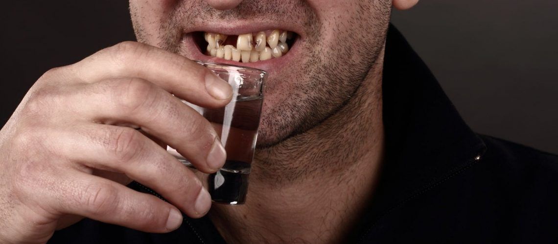 Man with teeth in poor health drinking alcohol