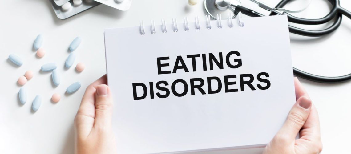 Text with words Eating Disorders on a Notebook with Doctor Tools and Medication