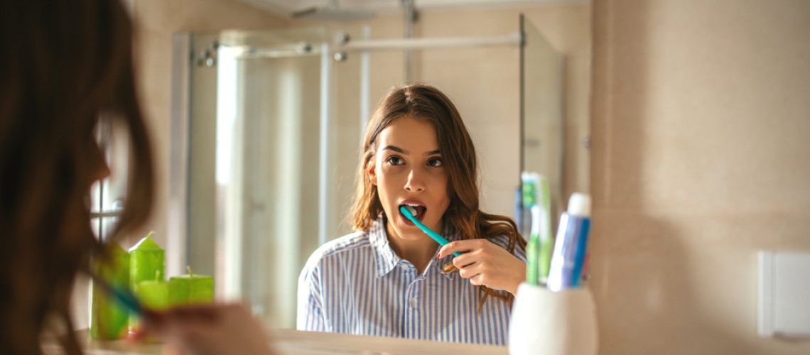 Portrait,Of,A,Beautiful,Woman,Brushing,Teeth,And,Looking,In